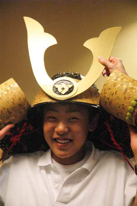 Japanese exchange student Takara Yamamoto is all smiles Wednesday as he tries on a decorative samurai helmet in Auburn City Hall. Yamamoto and six other students are visiting the Kent-Auburn area through a sister cities group that operates in conjunction with both cities and the Japanese city of Tamba.