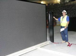 Daktronics employee Paul Winters stands by the Kent Event Center’s new display and scoreboard.