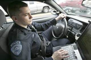 Kent Police Officer J. Bishop runs automobile license plates through a database using his patrol car’s laptop while patrolling Thursday. In spite of some financial belt-tightening by the city