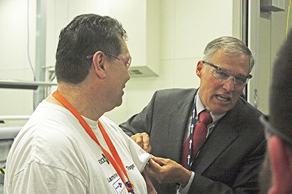 Gov. Jay Inslee puts a Washingtonian of the Day apple pin on Larry Ruffino