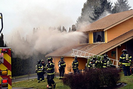 Firefighters work to put a house fire on Friday afternoon in the 10200 block of Southeast 228th Street in Kent.