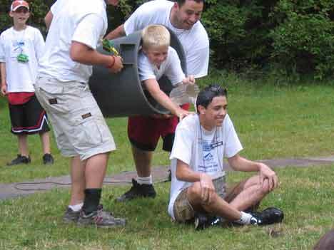Camp Waskowitz counselor Jimmy Candella gets a surprise soaking from a camper in a trash can as part of a skit performed for campers' families.