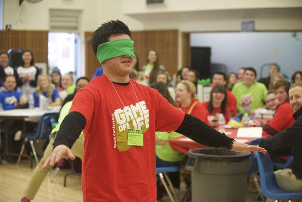 A blindfolded student searches for a chair during a game of blind musical chairs last year at the Game of Life Youth Conference lunch break at Kent Commons.