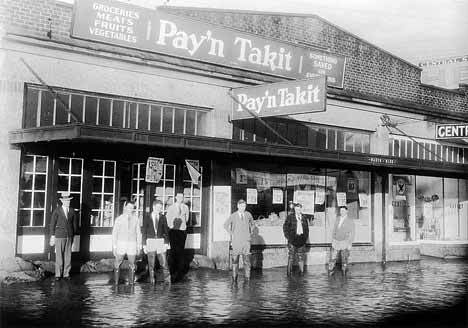 The Pay’n Take It Grocery on Kent’s Central Avenue saw standing water during the Green River flood of 1934. Two people identified in this photo are Claude Fielding