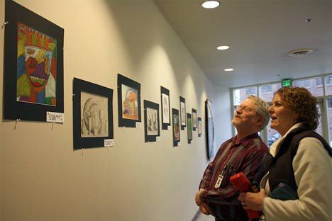 Kent city employees Margaret Bishop and John Rostad view some of the Kent School District student art work that will be part of Kent Student Art Walk March 7-18 in downtown Kent. They're looking at a pastel picture from Mill Creek Middle School student Charles Gapasin.