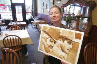 Leslie Armstrong holds a painting she did entirely with coffee as a tribute to Paul Newman. It depicts Newman in his role as Butch alongside Robert Redford in the movie