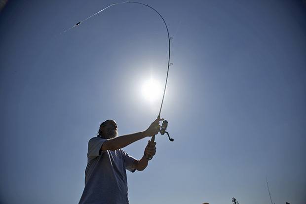 Leo Davis casts his line as he enjoys the sunshine on a recent sunny Monday afternoon in Kent. Davis has been fishing at Lake Meridian for 30 years.