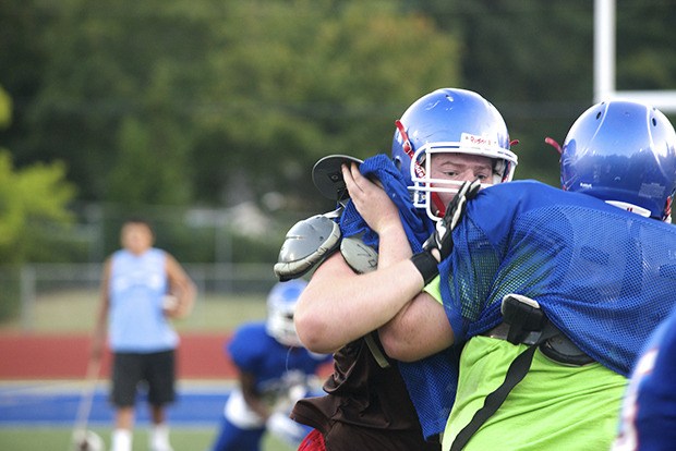 In the trenches: Kent-Meridian center Tanner Torr muscles up a defensive lineman during summer drills Monday. The Royals will field a big