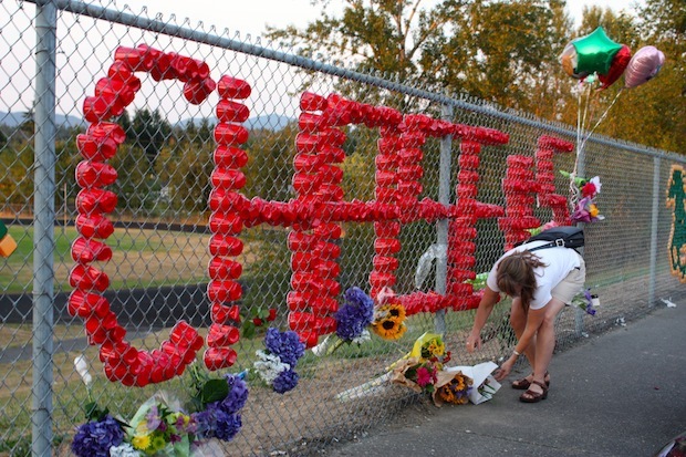 Susan Tostenrude adds a bouquet of flowers to a memorial honoring the late Chase Stancil at Kentridge High School on Friday evening. Family