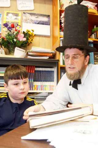 Jacob Cantrell reads through a biography of Abraham Lincoln Feb. 12 with his teacher John Rief. Rief wears his homemade Lincoln outfit to school once a year in observance of Presidents' Day.
