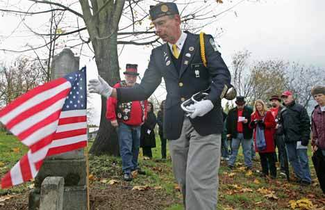 Dave Davis of the American Legion’s Kent Post sets a flag at the grave of a Civil War veteran Kent’s Saar Pioneer Cemetery. He also played “Taps” on the trumpet during the event.