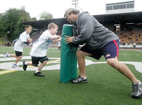 Seattle Seahawk Owen Schmitt takes a hit from camper Grayson Wuelfing during a drill at the third-annual ‘Karney’s 44 Kids Camp