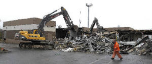 A crane demolishes a portion of the former King County Journal editorial offices March 26 in Kent. The remainder of the building will house Holmes Electric