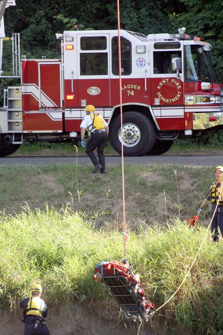 Kent firefighters use a ladder truck and basket to pull a man Tuesday from the Green River shore after two people rescued him from a possible drowning.