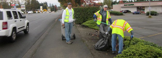 Volunteers from the Kent Chamber of Commerce East Hill Partnership clean up trash recently along Benson Road as part of the city’s Adopt-A-Street program.