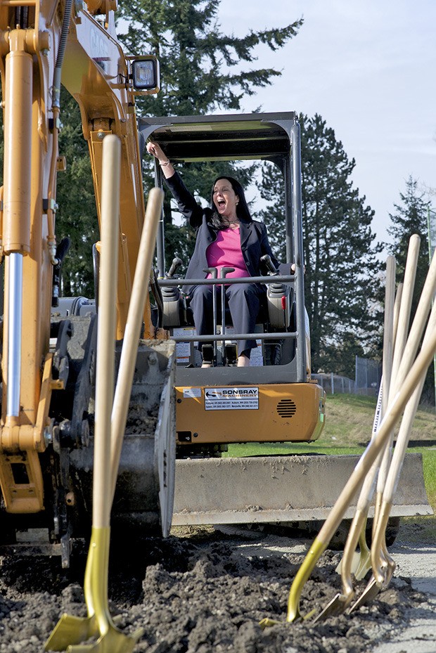 GRCC President Eileen Ely cheers after she uses a backhoe to break ground for the new trades building. Construction will begin soon on the building and is expected to be completed in 2015.