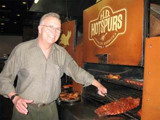 H.D. Hotspurs owner Dick Lowe checks on a rack of ribs in the restaurant’s barbecue pit