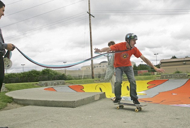 Kent Parks Facilities' Mike Hattrup rides through a ribbon to celebrate the completion of the new mural at the Kent Lions Skate Park