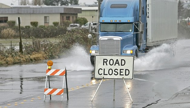 01/21/11 A semi-truck drives through the flooded 76th Avenue South ignoring the closure signs Jan. 21. Kent city crews closed 76th Avenue South from South 212th Street to approximately South 222nd Street Friday morning due to water over the roadway.