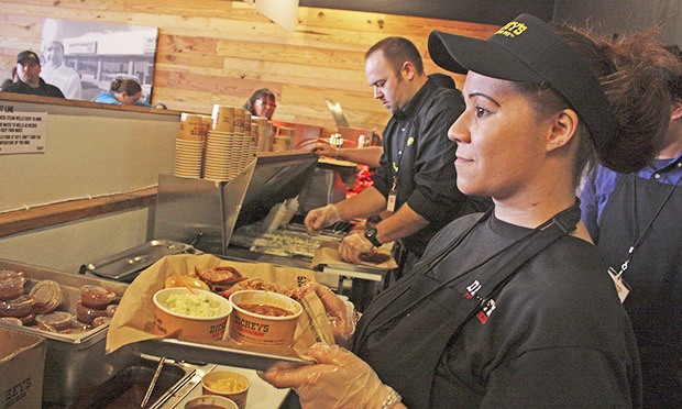 Angelina Morada serves up lunch to a busy grand-opening crowd Thursday at the new Dickey's Barbecue Pit at 1428 W. Meeker St. In the background is owner Ben Harris.