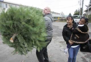 Toby Partney loads  a Christmas tree for Nicole Baker and her daughter Kaybrein