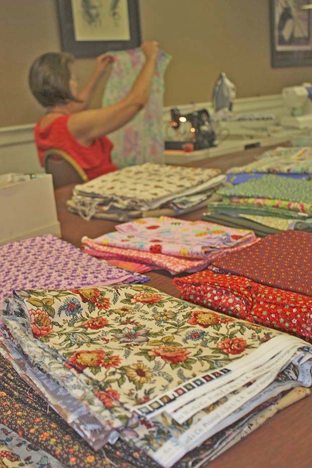 Marlys Powell goes to work amid fabric choices resting on a table.