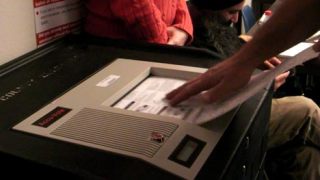 A voter slides a completed election ballot into the AccuVote machine at the Kent Commons Nov. 4.