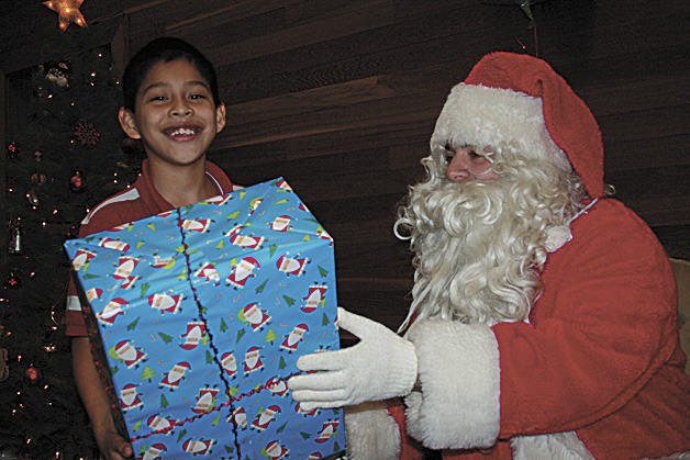 A Kent student receives a gift from Santa at the Meridian Kiwanis Club's 39th annual kids Christmas Party at the First Christian Church in Kent.