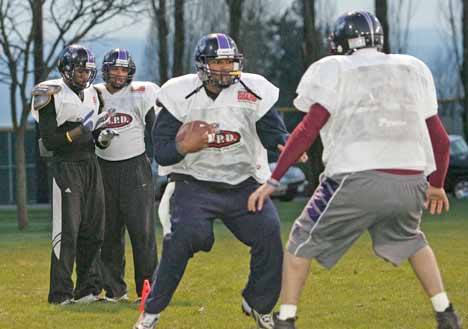 Kent Predators’ quarterback Charles McCullum tries to scramble by a teammate during a warmup drill at Kent Memorial Park on Thursday
