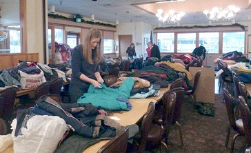 Kiwanis volunteer Suzanne Berrios helps organize the many articles of winter clothing given during a fundraising lunch Dec. 10 at the Kent restaurant she and her husband Jim Berrios run