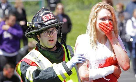 Kent Fire Fighter Alex Richardson walks Kentwood High School student Anna Sidor off the scene of a car crash in a staged disaster May 20 at KHS. The mock crash was part of Kent Fire's Gift of Life presentation