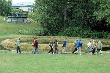 A tour group strolls past an earthen structure June 16 at Kent's Mill Creek Canyon Earthworks Park. The tours was to give the public a chance to learn about the park's creator