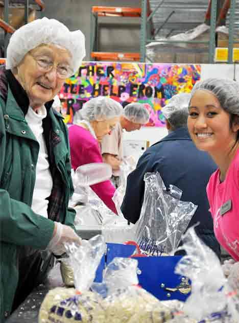 Barbara Hallock and Shanel Bell of Farrington Court Retirement Community smile as they put the final touches on packing food items at the Northwest Harvest warehouse in Kent Dec. 3