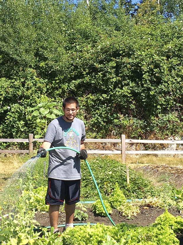 Andy Satkowski waters the edible garden at Highline College earlier this year. The garden gives students like Satkowski