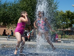 Kids try to stay cool in the Town Square Plaza fountains in downtown Kent.