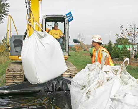 Excavator operator Glenn McGee and Steve Vorheis place giant sand bags along the Green River Trail between S. 212th St. and S. 196th St. near the Three Friends Fishing Hole.
