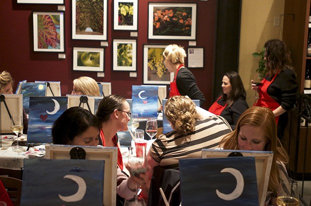 Visitors to Reds Wine Bar’s Corks and Canvas event work on night sky watercolor paintings. Corks and Canvas