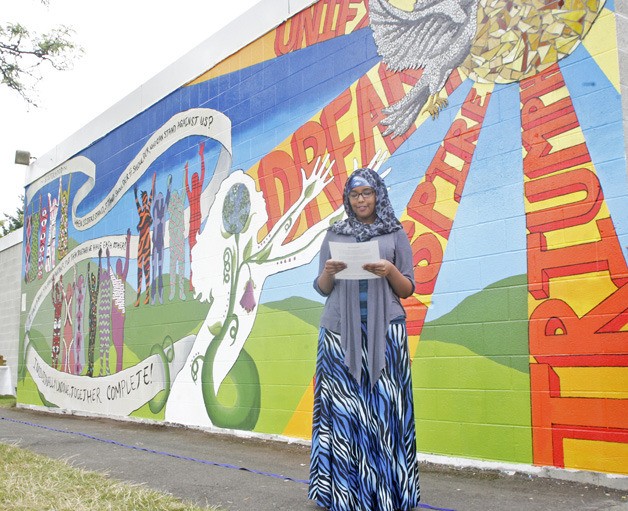 Siham Jigre reads the dedication for the mural during the unveiling ceremony