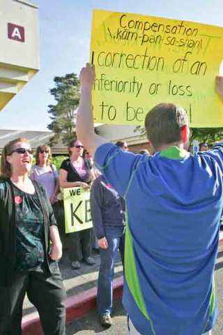 Mill Creek Middle School teacher Tyler Baril holds up a sign to lead the chanting Wednesday at a rally by the Kent Education Association outside school District offices.