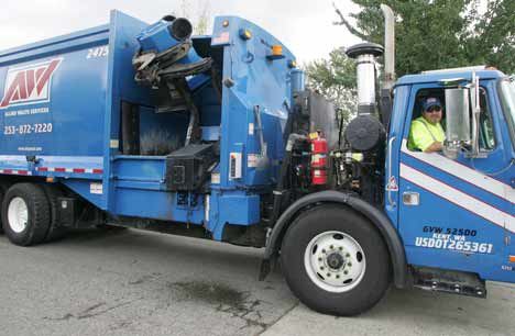 Allied Waste Services’ driver John Egan Jr. demonstrates how the waste-hauling truck grabs a recycling bin last summer.