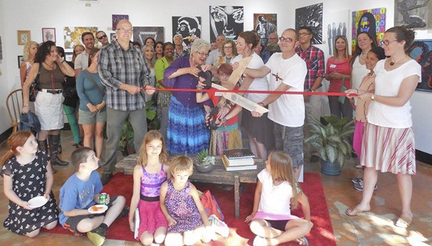 Mayor Suzette Cooke helps cut the ribbon at an Aug. 6 open house for the Rusty Raven Studio in historic downtown Kent.