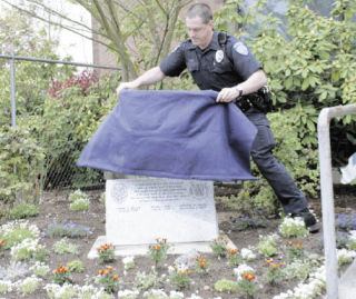Officer Tim Lontz on Tuesday unveils a memorial at Kent City Hall’s Courtyard Plaza in honor of late lawmen Marshal Harry Miller