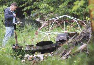 Kent code enforcement officer Brian Swanberg investigates a residential property in Kent Tuesday that had junk in the yard and vacant
