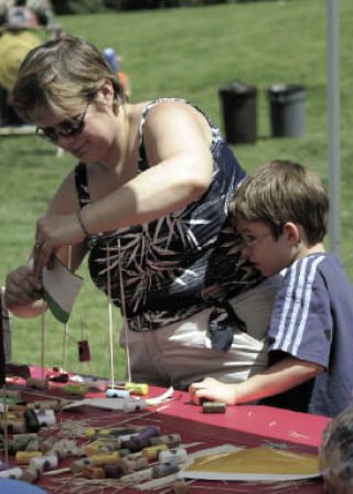 Tina Casper and her son Timothy Casper build cork boats as an activity at last year’s Fourth of July Splash. This year’s splash could see a reduced fireworks display