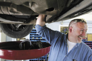 Robert Stone laughs as a coworker gives him a hard time while performing an oil change on a city vehicle Wednesday.