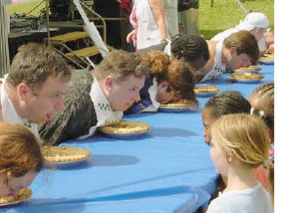 Contestants wolf down pies while onlookers watch in amazement