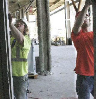 Brandon McLaughlin (left) and Jeremy Galstad of Barkley Dean Construction set a door jam for an electrical room outside of the main arena at the Kent Events Center July 16.