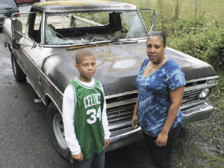 Kelly Carroll and her son Robert stand with Carroll’s burnt-out truck Wednesday in Kent.  The truck made Carroll’s charity organization