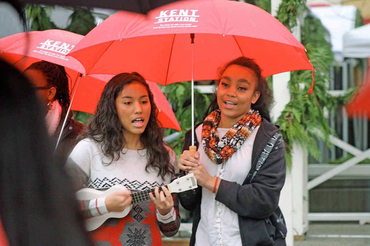 Kayla Palmer, strumming the ukulele, and Cyan Smith of the Kent-Meridian High School Choir sing “Baby, It’s Cold Outside” in front of Santa’s House at Kent Station last Saturday. The senior duet was part of the festivities as families and their children awaited the arrival of Santa Claus. MARK KLAAS, Kent Reporter