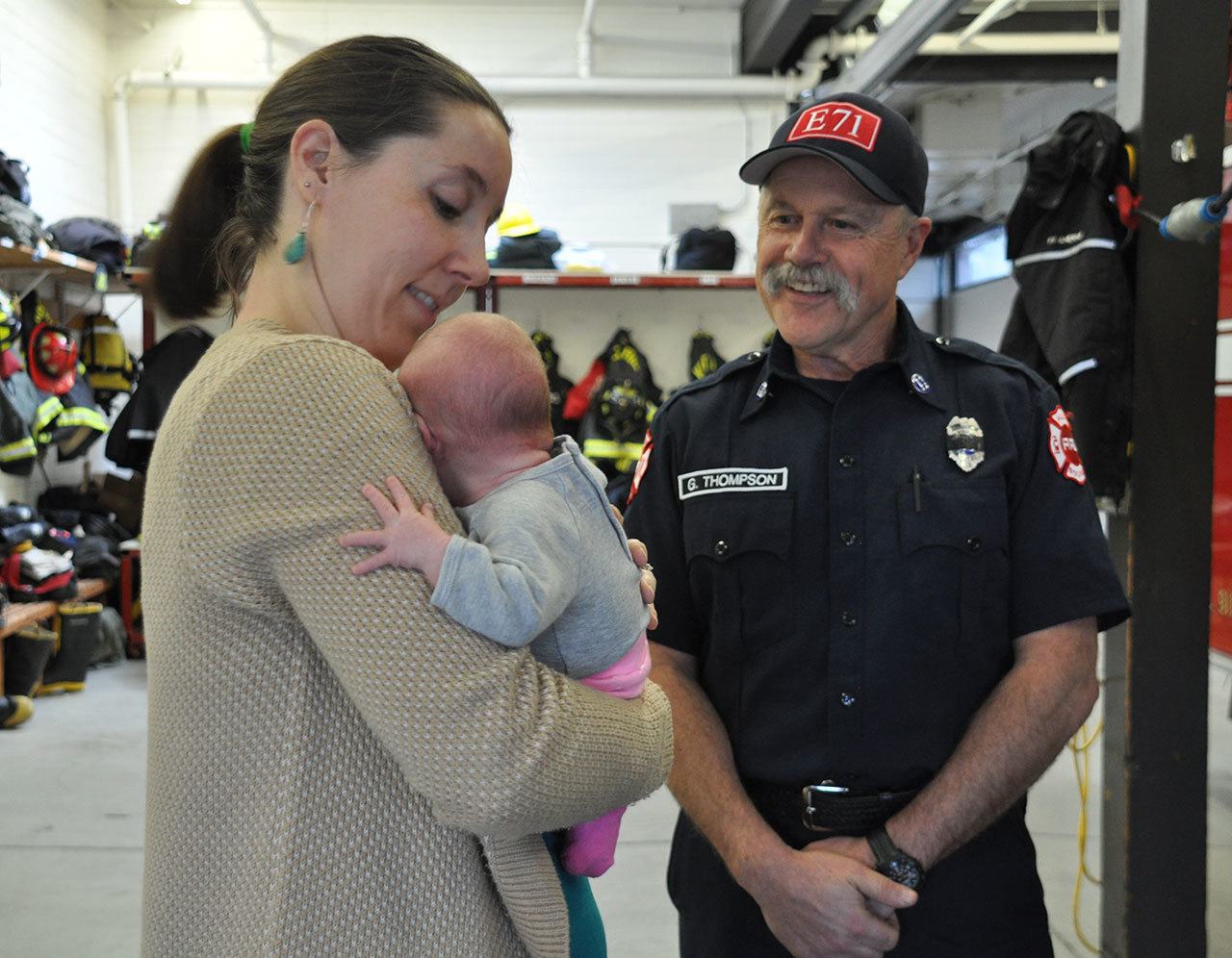 Kelley Lowery holds her 1-month-old daughter, Mia, while visiting with Puget Sound Fire Capt. Guy Thompson who delivered Mia at Fire Station 77 on Dec. 21. HEIDI SANDERS, Kent Reporter